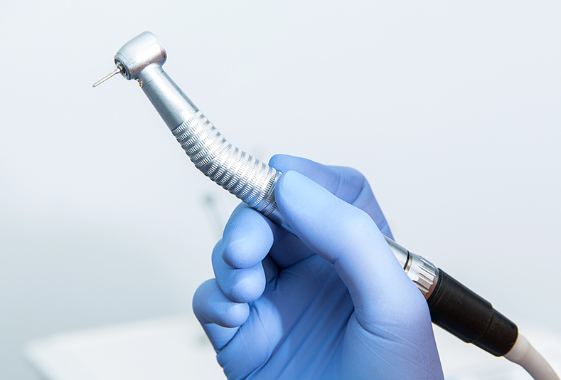 La mano di un dentista che tiene un manipolo 