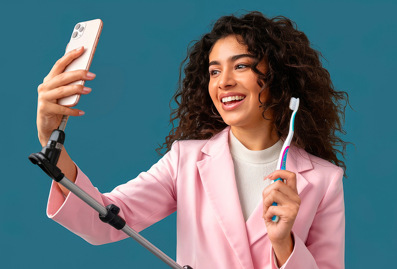Ragazza con smartphone che registra un video educativo con spazzolino in mano