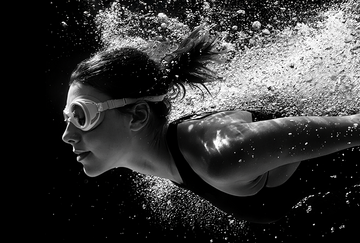 donna con occhialini da piscina che nuota sott'acqua