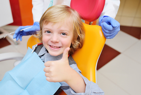 bambino dal dentista con pollice alzato