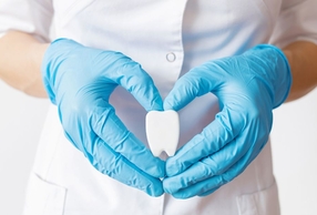 Mani con guanti che formano un cuore con al centro un dente