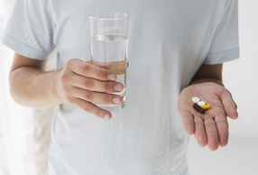 primo piano su mani di medico che tiene un bicchiere d'acqua e delle pillole