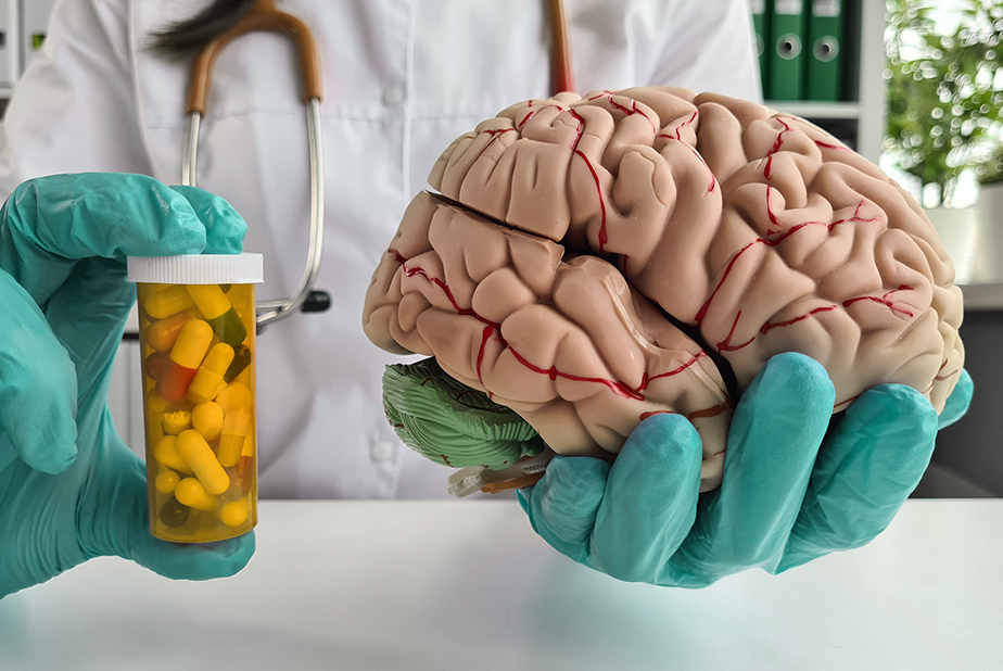 Effetto Nocebo: quali implicazioni in odontoiatria? dottore tiene in una mano un modello anatomico del cervello e nell'altra un tubetto di farmaci