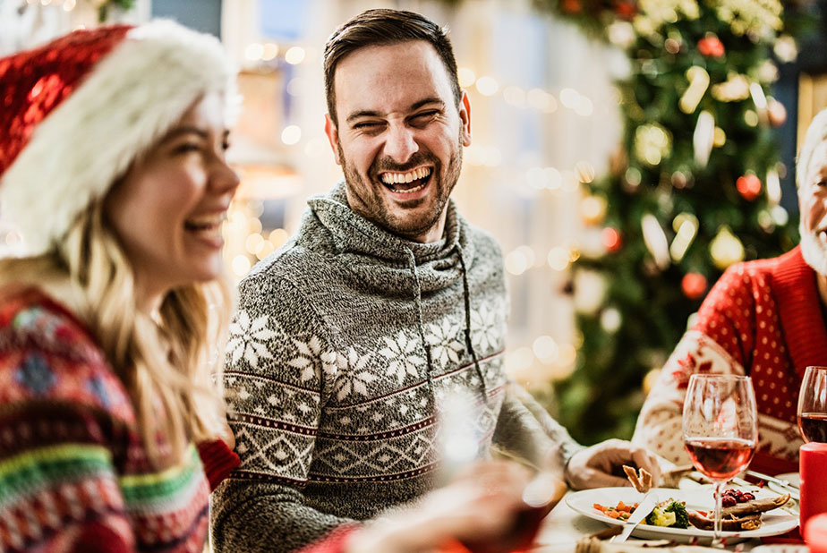 Festività: occhio alla salute orale! Regole salva-denti per Natale (e non solo) Uomo a tavola durante le festività natalizie che sorride