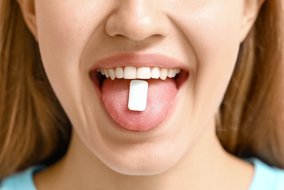 Chewing gum senza zucchero: un aiuto quotidiano per la bocca Primo piano della bocca di una donna con una gomma