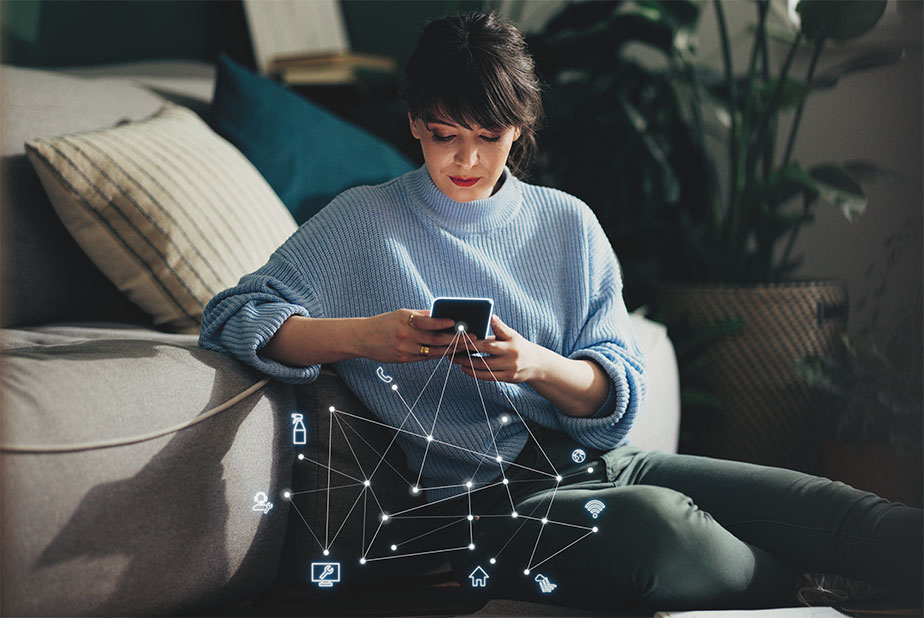 Donna che controlla riunito da smartphone dal divano di casa