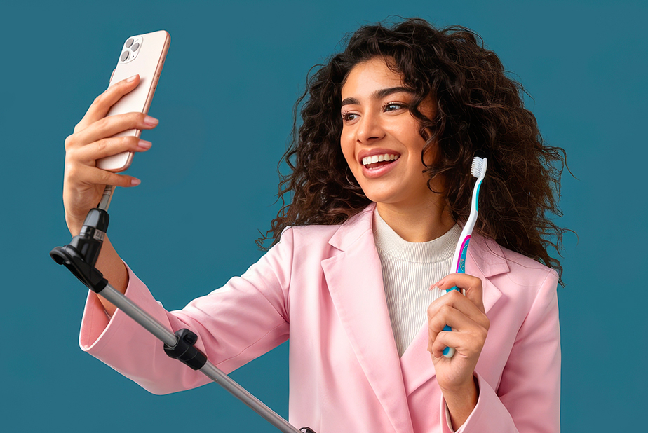 Ragazza con smartphone che registra un video educativo con spazzolino in mano