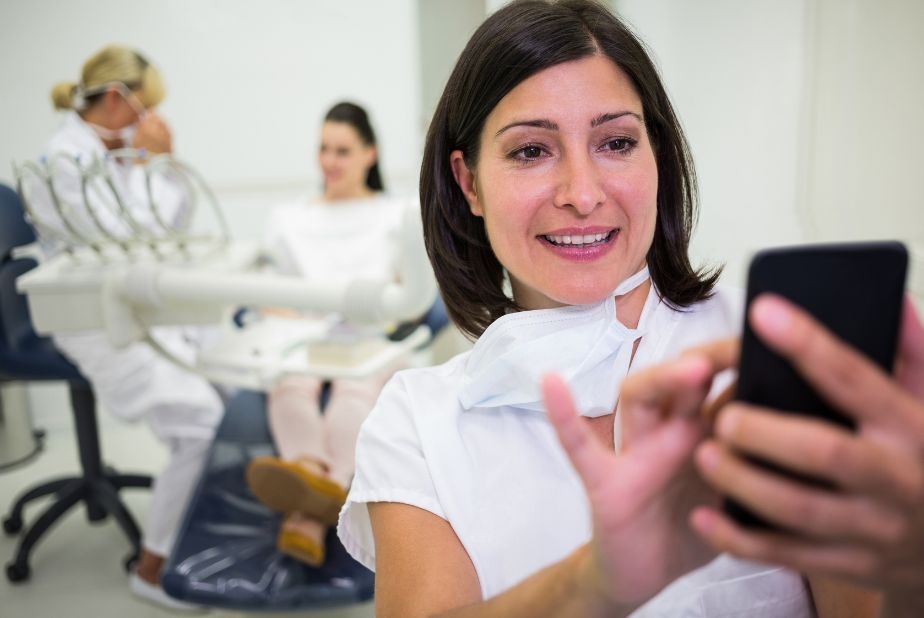 Marketing per lo studio dentistico: la fiducia si costruisce prima della prima visita Paziente con smartphone in studio